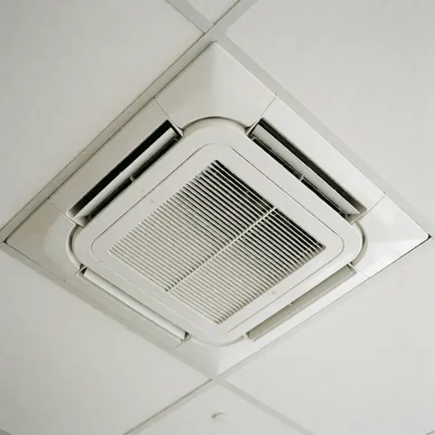 Close-up view of a white cassette ceiling air conditioning unit installed in a commercial interior space, showcasing its clean and modern design.