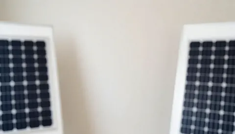 Two white-framed solar panels on a light neutral background, ideal for adding text, no people, for solar energy business