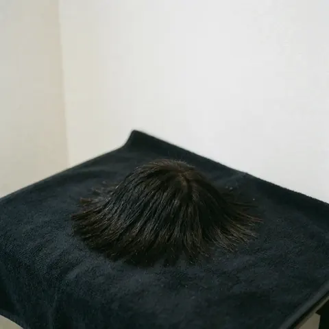 A close-up view of a freshly cut hairstyle with a white towel draped around the neck, showcasing the clean lines and professional finish of the barber service.