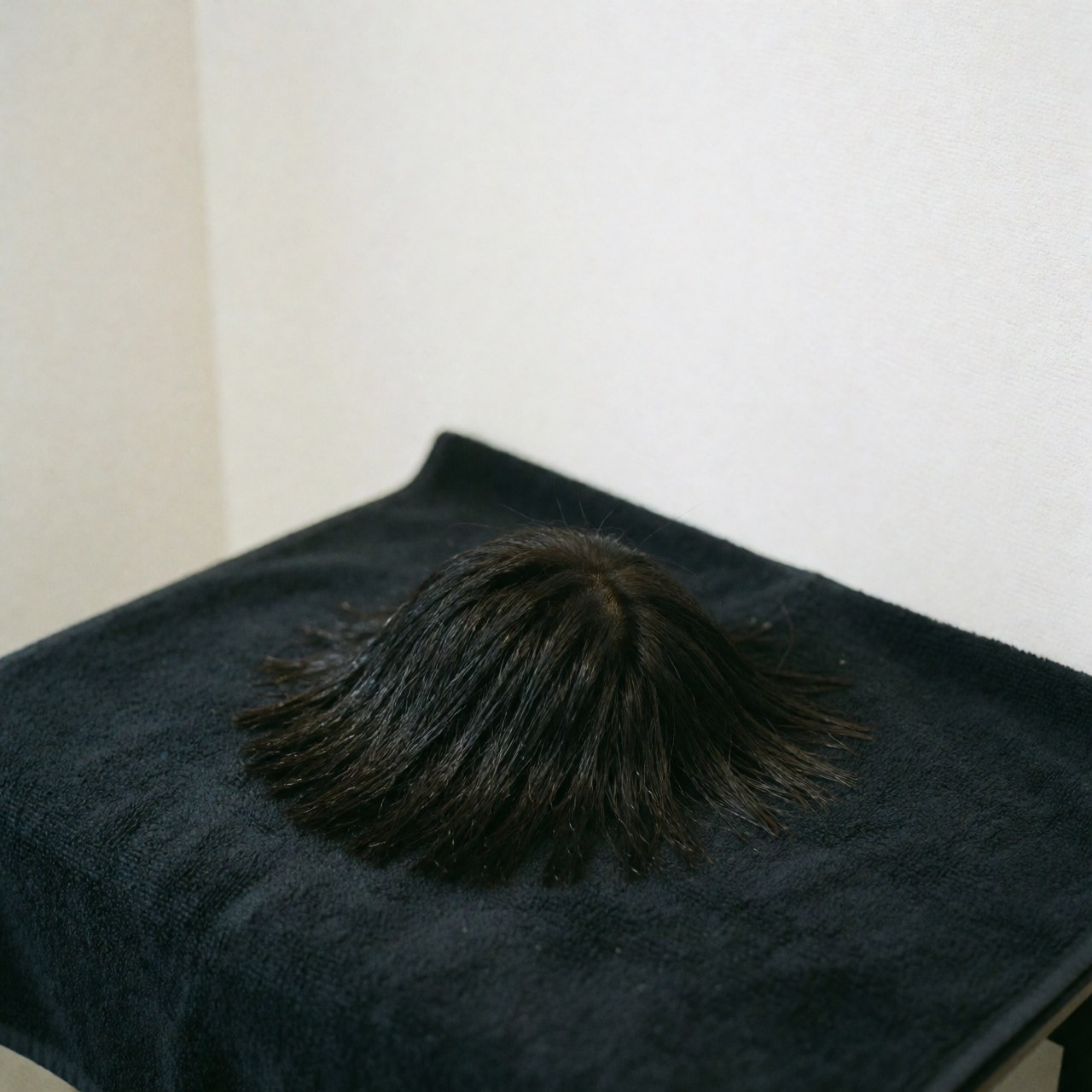 A close-up view of a freshly cut hairstyle with a white towel draped around the neck, showcasing the clean lines and professional finish of the barber service.