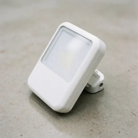 Close-up of a sleek white LED security light mounted on a textured concrete wall, highlighting its modern design and durable construction.
