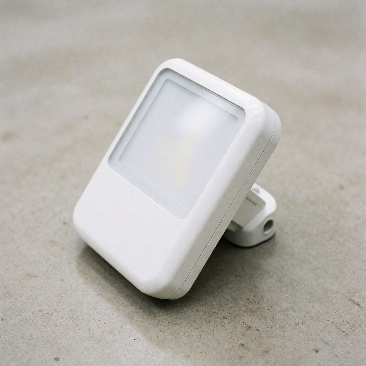 Close-up of a sleek white LED security light mounted on a textured concrete wall, highlighting its modern design and durable construction.