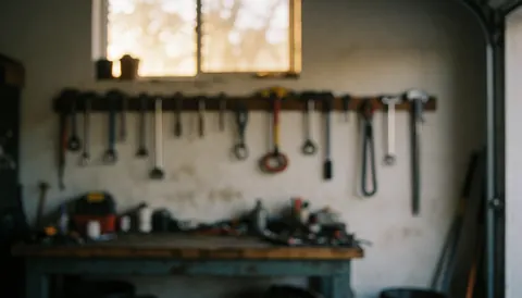 Warmly lit workshop background featuring organized hanging tools and a sturdy workbench, providing a professional texture ideal for commercial text overlays in plumbing and repair contexts.