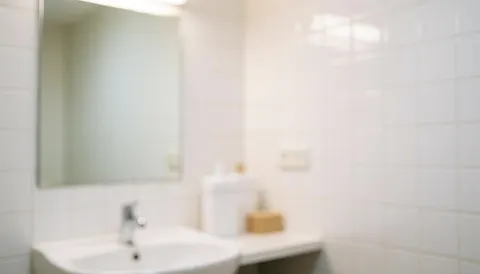 A clean white tiled wall featuring a modern bathroom mirror and sink, providing a serene and professional background suitable for spa and massage business marketing materials.