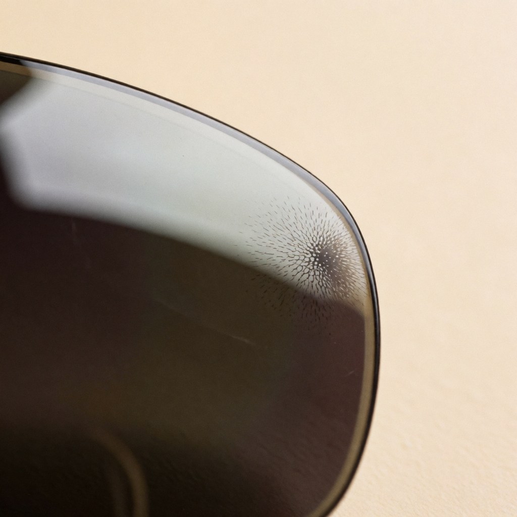 Close-up view of a photochromic eyeglass lens transitioning from clear to dark as it reacts to uv light exposure, highlighting the material technology.