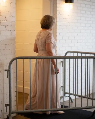 A woman in a formal dress walks through a metal security barrier at the entrance of an indoor event, ensuring safe and orderly access for guests.