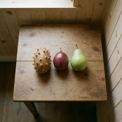 Assortment of fresh local fiber-rich fruits including kiwano and passion fruit arranged on a wooden surface near a window for healthy nutrition