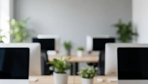 Modern marketing agency workspace featuring desks, computers, and green plants with a blurred background suitable for professional text overlays