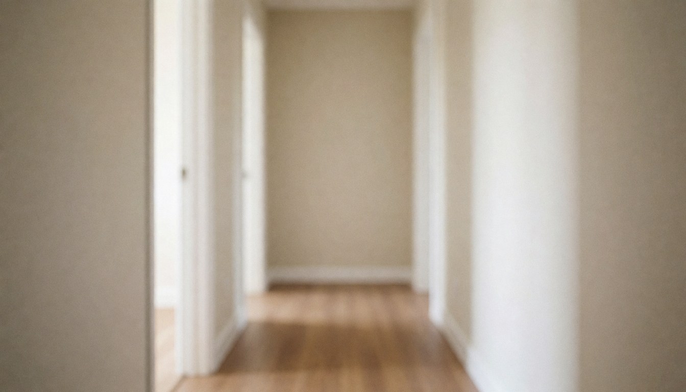 A serene residential hallway featuring beige walls and a wooden floor illuminated by soft natural light, serving as a neutral background for text.