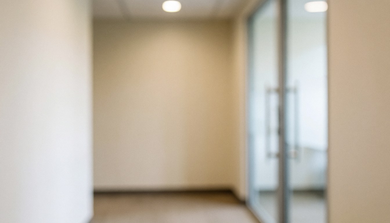 Softly blurred beige office hallway with glass doors, providing a neutral professional background suitable for business text and logos