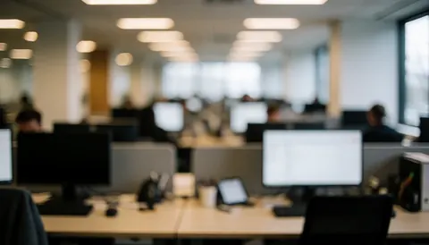 Soft focus background of a professional office workspace featuring a desk, computer monitor, and ambient lighting suitable for business presentations