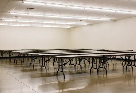 Empty community storage space featuring metal tables, polished floors, and fluorescent lighting, ready for events and text overlays