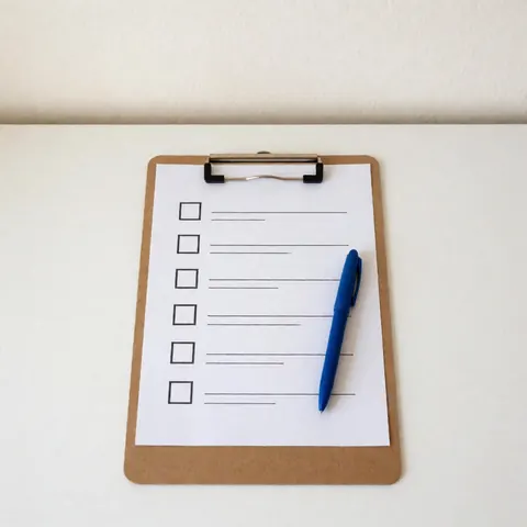 A clipboard with a checklist and a pen resting on a wooden desk surface, symbolizing organization and planning for business consulting tasks.