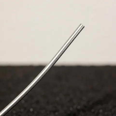 Detailed view of lead-free soldering wire with a metallic shine against a dark textured background, highlighting the material used in professional plumbing work.