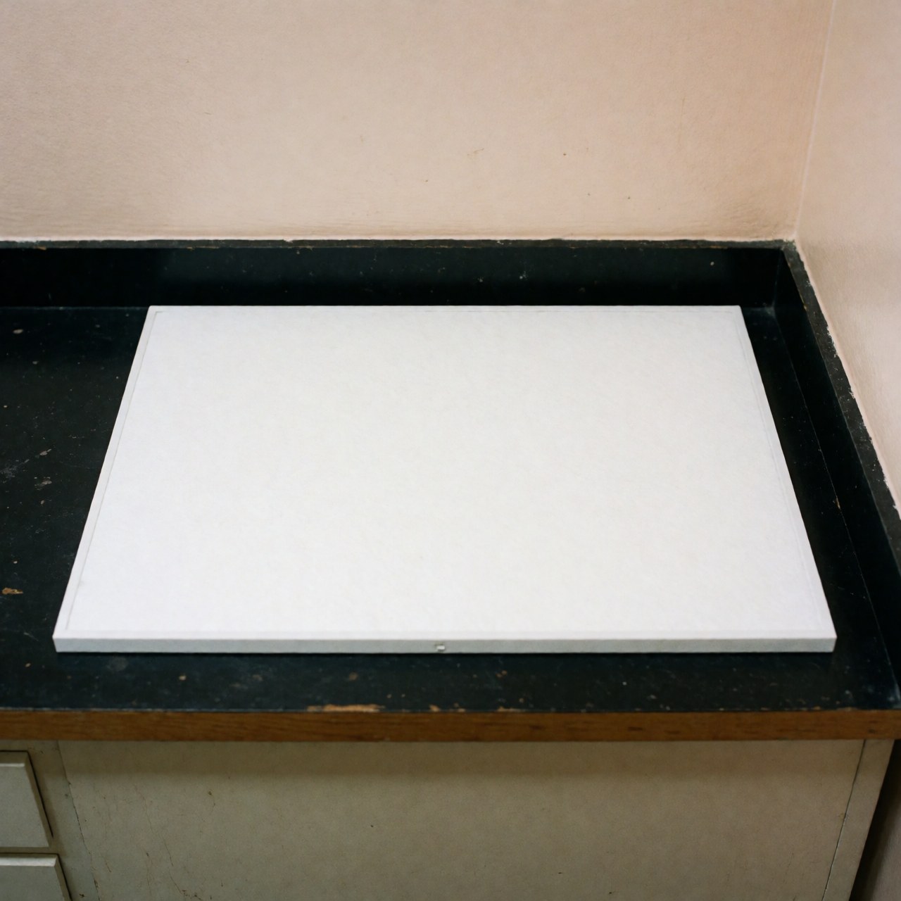 A clean white rectangular replacement air conditioning filter lying on a work surface, ready for installation or maintenance.