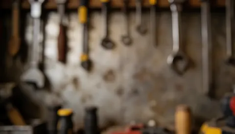 A blurred workshop background featuring hanging tools, screws, ropes, and industrial textures on a wall, providing a warm, textured surface suitable for text overlay in construction and business contexts.