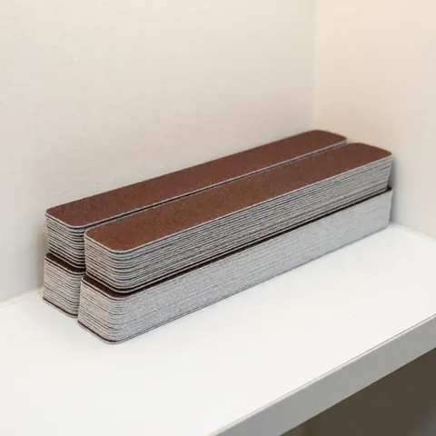 Neatly stacked emery boards with visible grit texture on a clean white surface in a professional nail salon setting