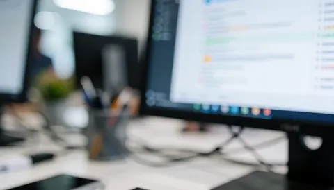 Professional office desk with computer monitors and cables, featuring soft bokeh and cool tones, ideal for marketing agency text backgrounds.