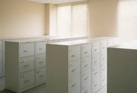 An empty HR office featuring white filing cabinets, beige walls, and natural light, conveying order and security for business records.