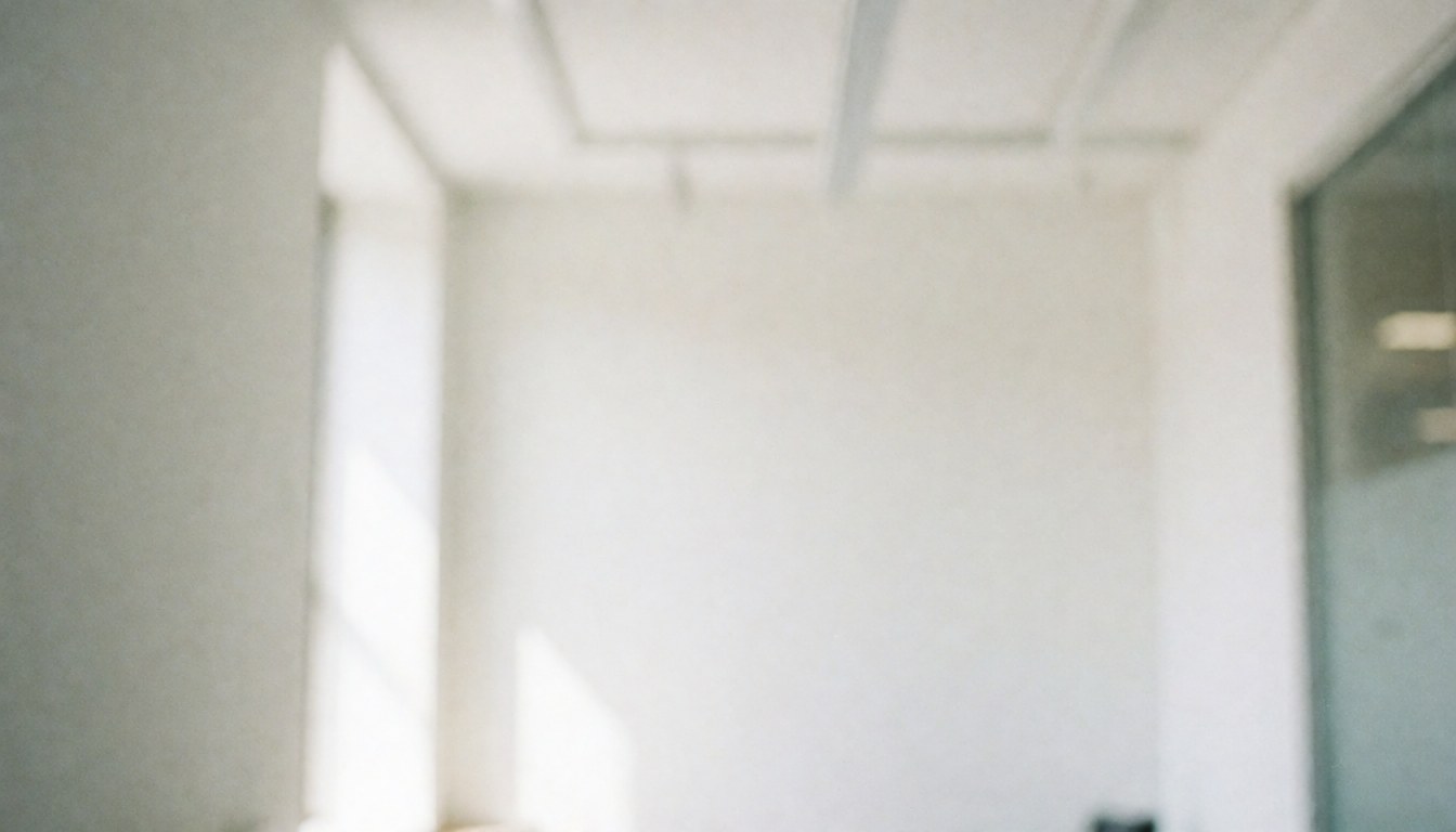Empty modern office interior with white walls and soft natural lighting, providing a clean minimalist backdrop for professional business presentations and text overlays.