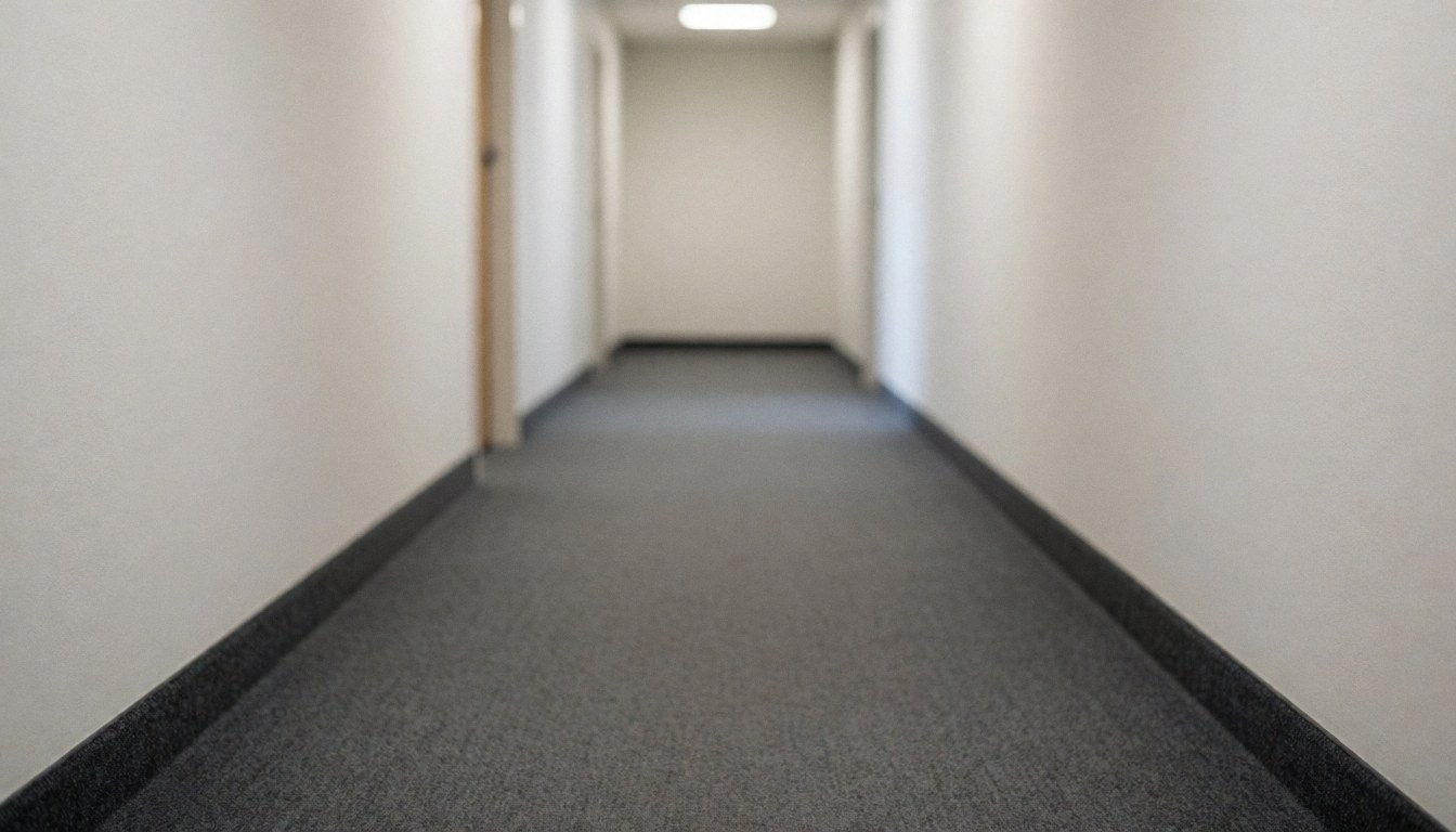 A blurred image of a residential hallway with carpeted floor and walls, serving as a clean background for text overlays.