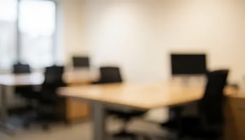 Soft focus view of a contemporary office space featuring desks and chairs with warm ambient lighting, creating a professional atmosphere suitable for business presentations and text overlays.