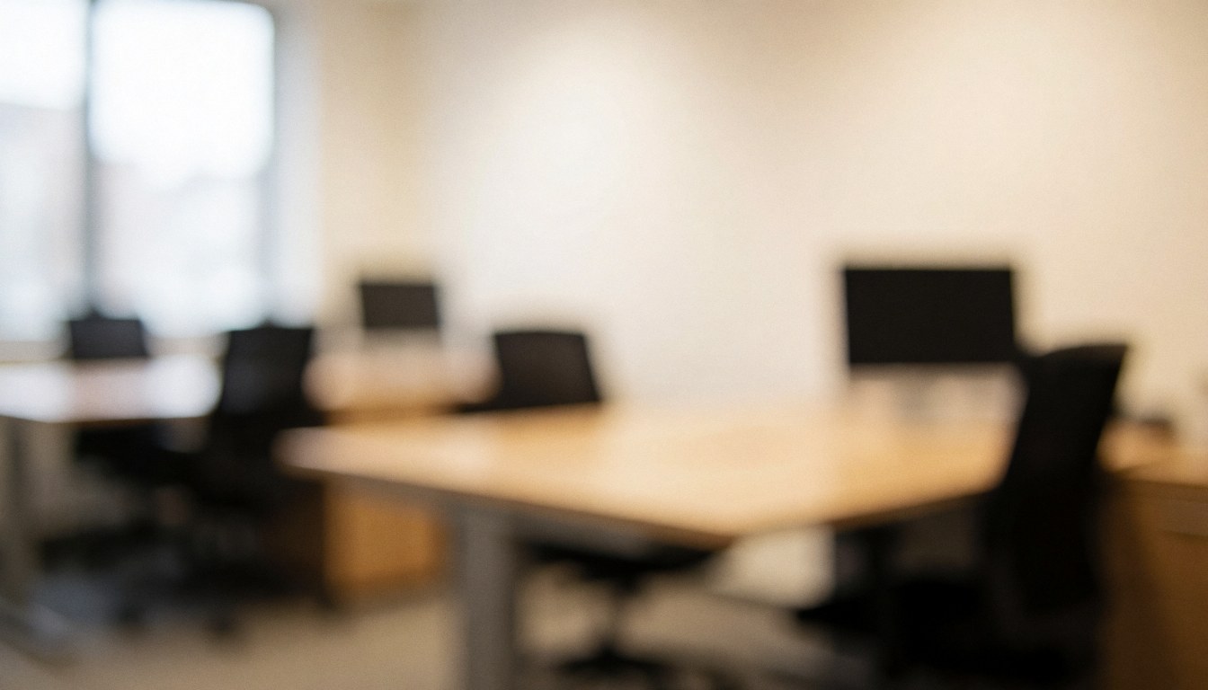 Soft focus view of a contemporary office space featuring desks and chairs with warm ambient lighting, creating a professional atmosphere suitable for business presentations and text overlays.