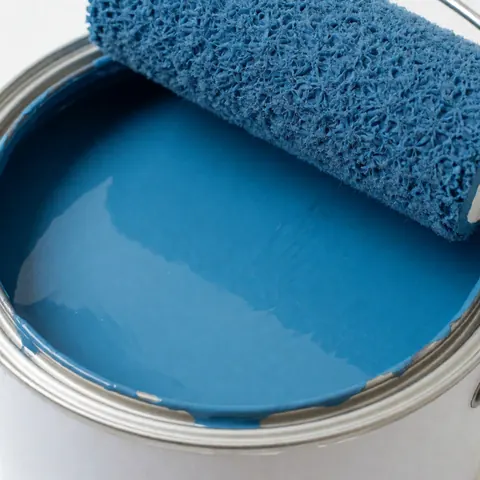 A can of fresh blue latex paint and a paint roller ready for interior wall renovation in a hardware store
