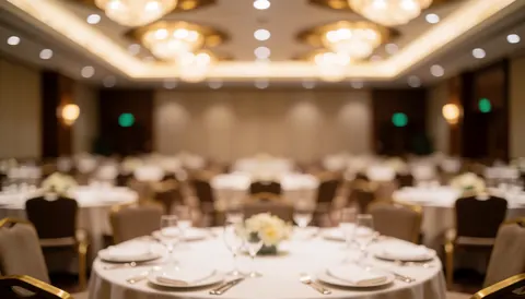 Blurred background of an elegant banquet hall featuring set tables, white tablecloths, wine glasses, and warm lighting suitable for text overlay
