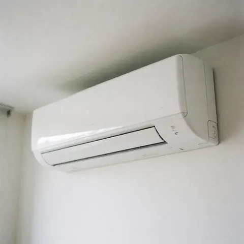 Close-up view of a modern white indoor air conditioning unit mounted on a clean white wall, representing efficient home climate control and residential HVAC technology.
