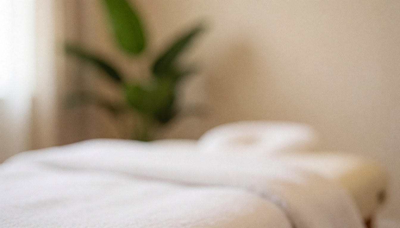 Soft focus background of a serene spa treatment room featuring neatly folded towels, greenery, and ambient lighting for relaxation and wellness.