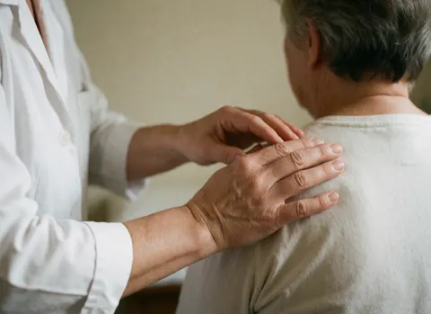 Close-up view of a therapist's hands applying gentle pressure to a client's shoulder during a relaxing spa treatment session