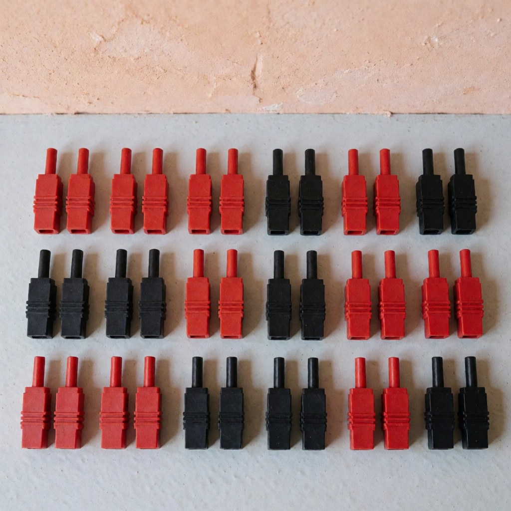 Top-down view of black and red mc4 solar connectors arranged on a textured gray surface with natural lighting, ideal for solar energy product displays.