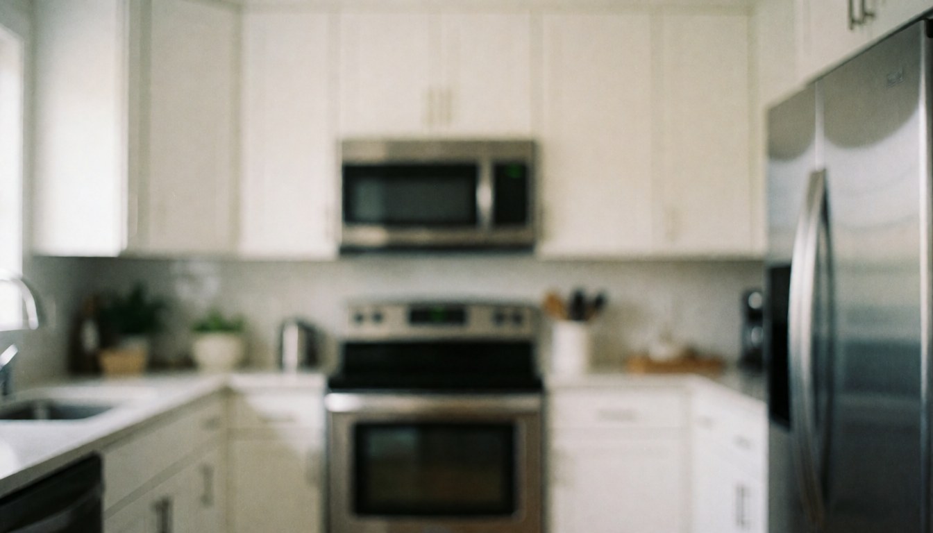 Blurred background of a modern kitchen featuring white cabinets and stainless steel appliances, suitable for text overlay in real estate marketing materials.