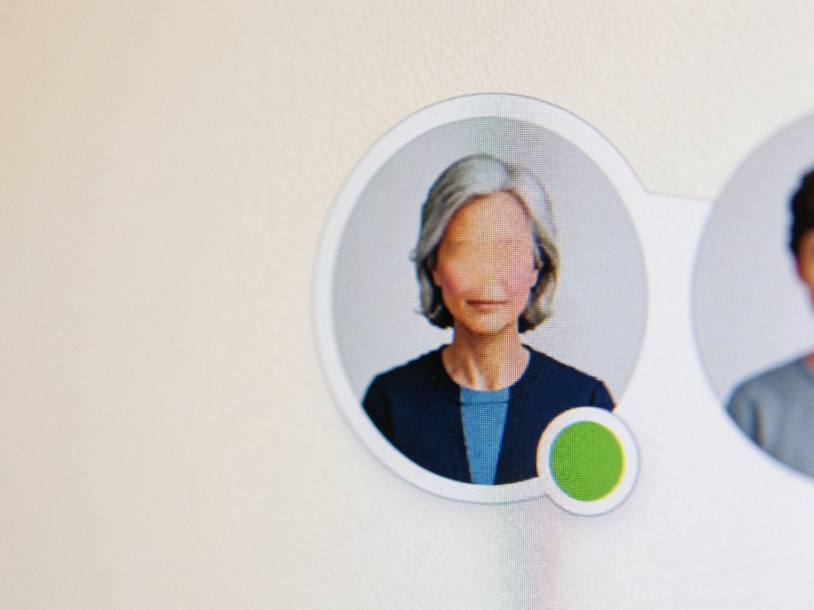 Close-up of a digital user avatar icon displaying a green status indicator on a screen against a warm-colored wall background