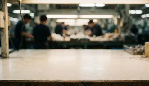 A soft focus industrial background suitable for text overlay, featuring blurred elements of a factory setting with hints of machinery and production areas.