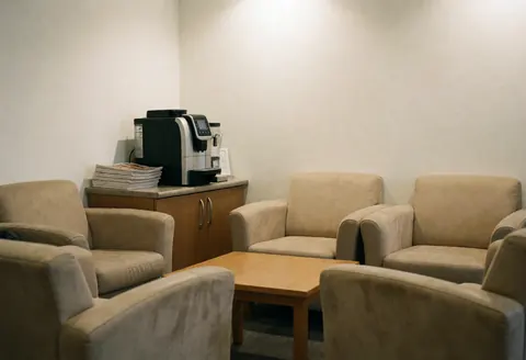 Cozy waiting area featuring beige chairs, a wooden table, and a coffee machine, designed for accounting clients.