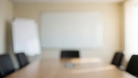 A clean and neutral corporate meeting room background featuring a conference table and whiteboard, ideal for business presentations and accounting text overlays