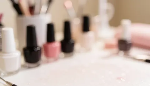 Soft blurred background featuring nail polish bottles, brushes, and manicure tools in warm tones for text overlay