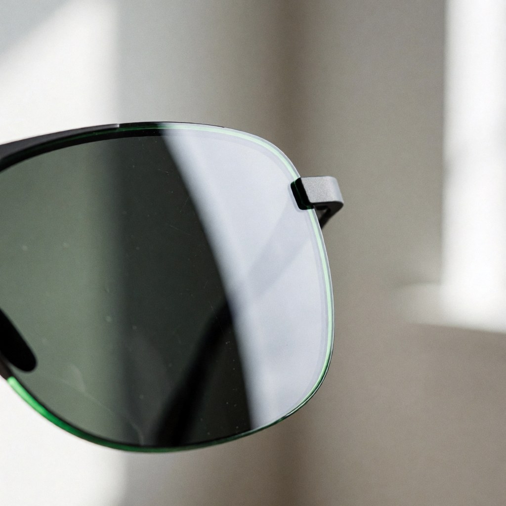 Detailed close-up view of a hydrophobic optical lens surface featuring distinct water droplets beading up, highlighting the water-repellent coating technology used in high-quality eyewear.