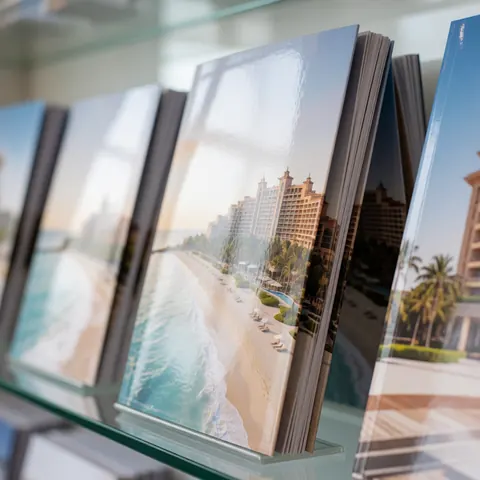 A luxury hotel brochure resting on a glass surface near a beach scene with palm trees and blue water