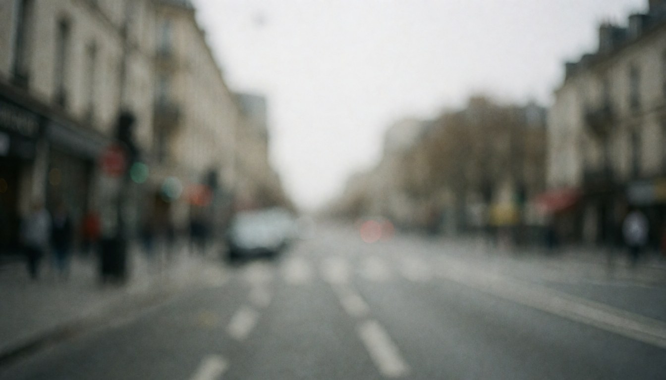 Out of focus gray urban street scene with blurred buildings and pavement under diffused light, serving as a neutral professional background for text or graphics.