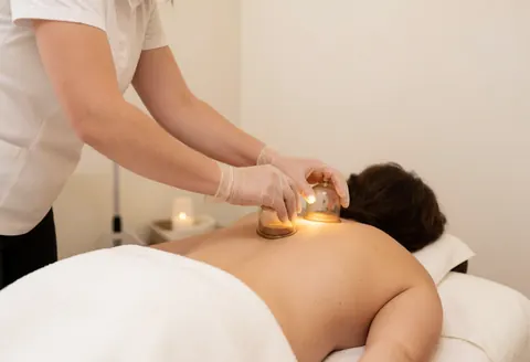 A therapist wearing gloves performs cupping therapy on a client's back during a relaxing spa session