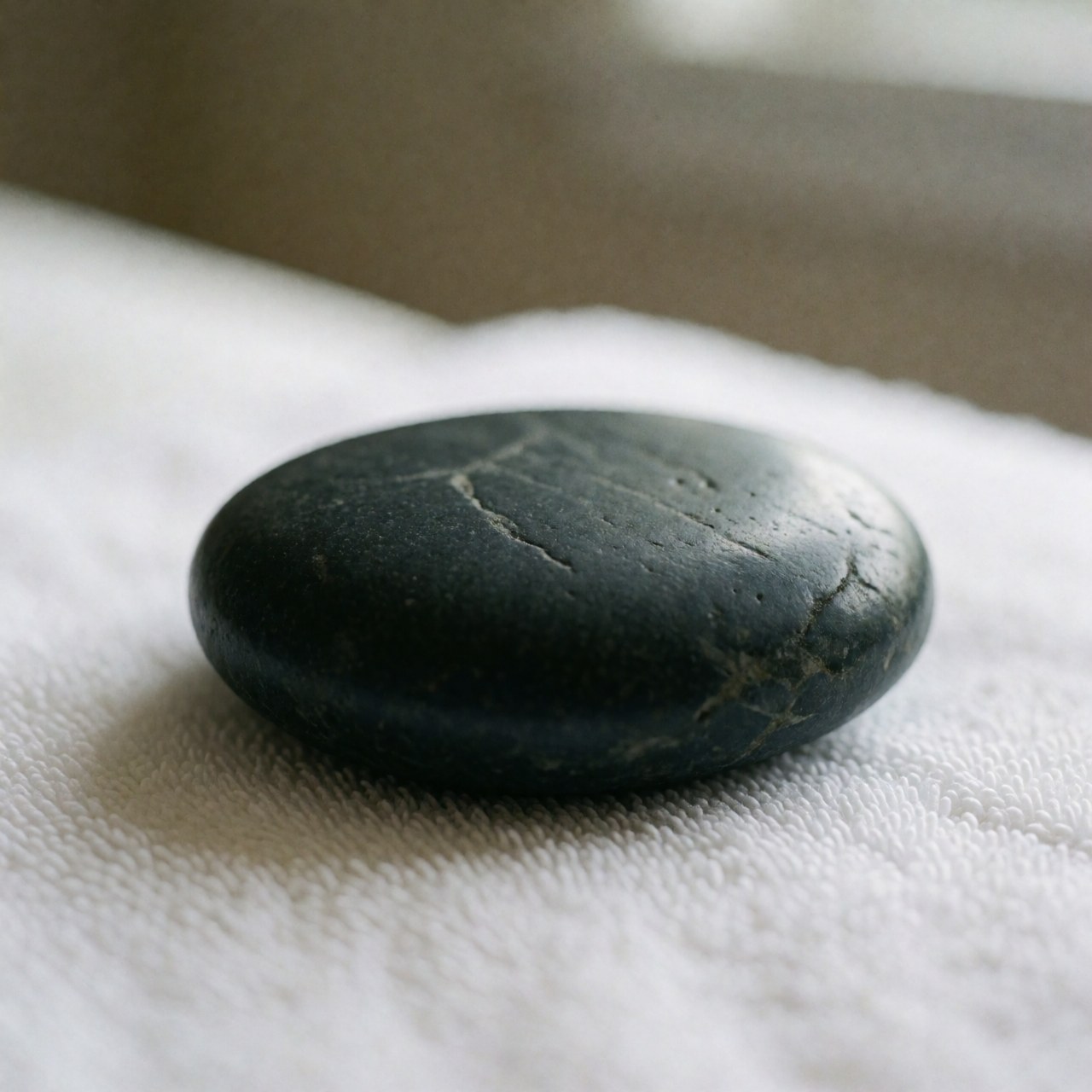 Clean basalt massage stone resting on a white towel, professional image for spa and wellness services