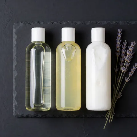 An overhead view of various massage oils, gels, creams, and spa stones arranged neatly for professional body care and relaxation treatments