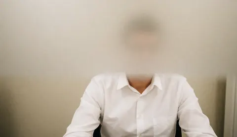 A person wearing a white shirt sits at an office desk with a blurred background, providing a clean space for business text and sales agreements.