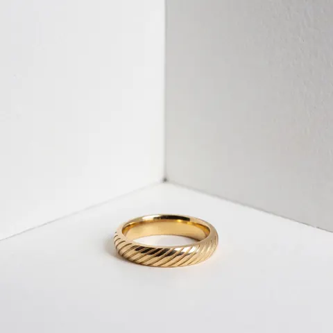 A detailed close-up of a personalized engraved gold ring displayed against a clean white background, highlighting the metal texture and craftsmanship.