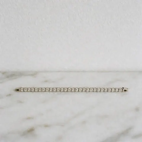 Shiny diamond earrings displayed on a white marble surface with professional lighting and symmetrical design for a jewelry catalog