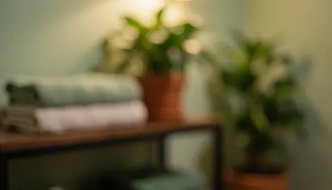A fisioterapia-avanzada background featuring folded towels and potted plants on a wooden floor, illuminated by warm light for health and wellness text overlays