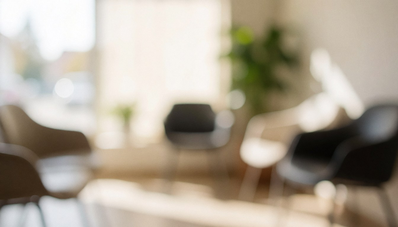 A softly blurred interior shot of a quiet waiting area featuring a chair and a potted plant, creating a calm and professional atmosphere suitable for text overlay.